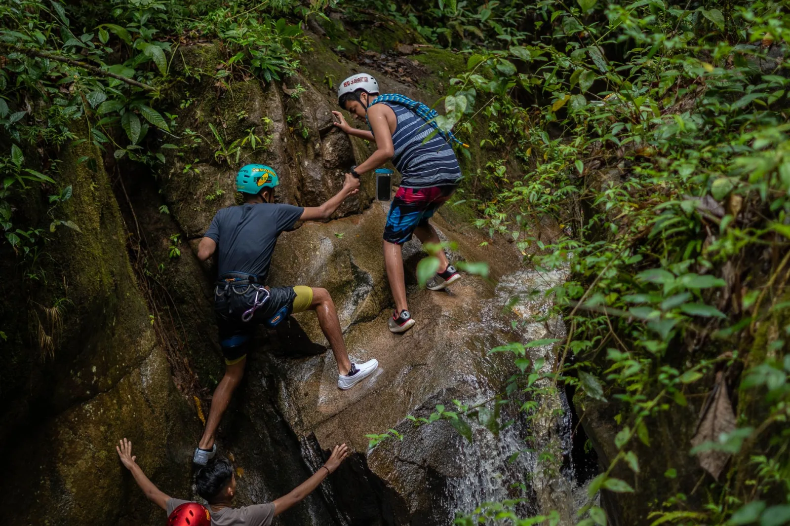 Group of adventurers scaling a rocky path amidst lush greenery in Peru, displaying teamwork and determination.