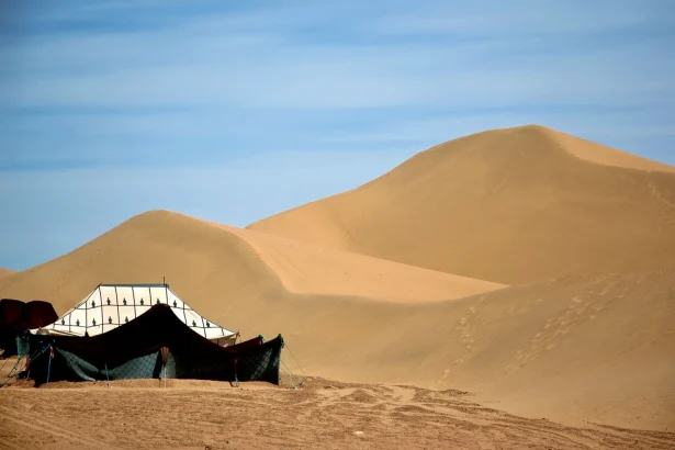 A traditional Berber tent set against the vast sand dunes of the Moroccan Sahara.