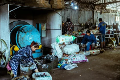 Workers sorting materials in a recycling plant, emphasizing manual labor in waste management.