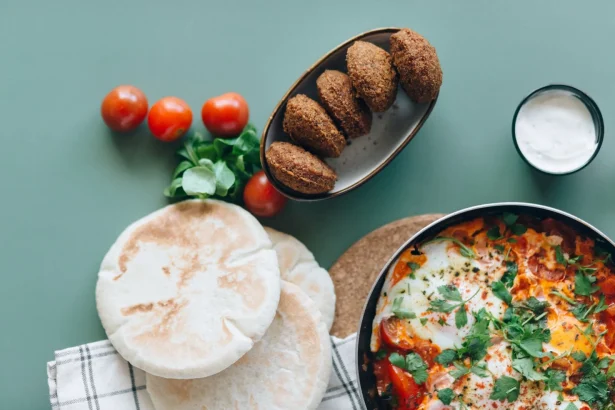 A delicious spread of Middle Eastern dishes featuring falafel, shakshuka, and pita bread on a green table.