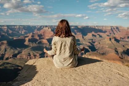 A woman practices meditation on the edge of the Grand Canyon, showcasing tranquility and nature's vastness.