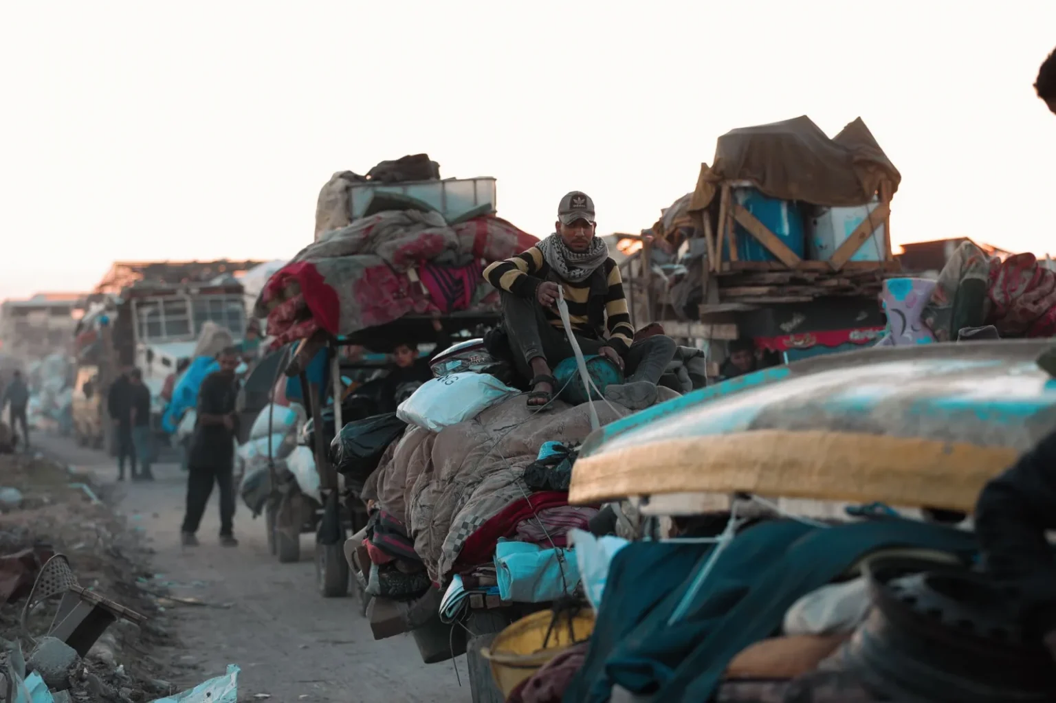 A group of people transporting belongings on a road, symbolizing hope and resilience.